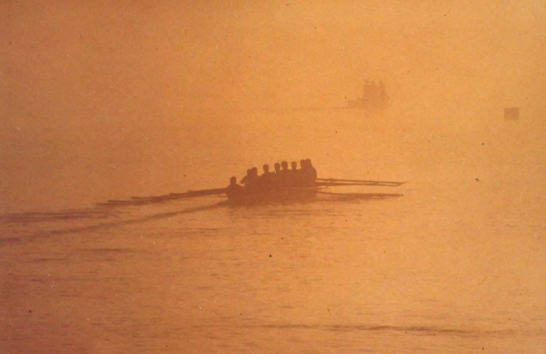 An eight rowing through golden morning fog on the Tennessee River, 1996–97 season.