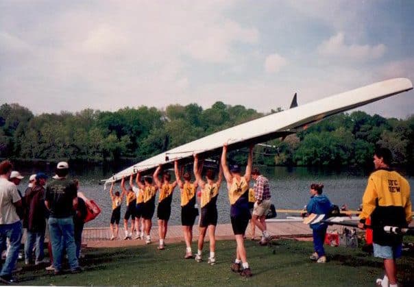 A crew carrying an eight down to the water.