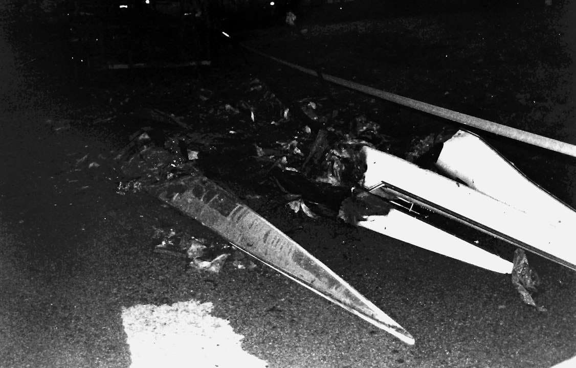 Pieces of a destroyed shell hull on pavement, photographed at night.