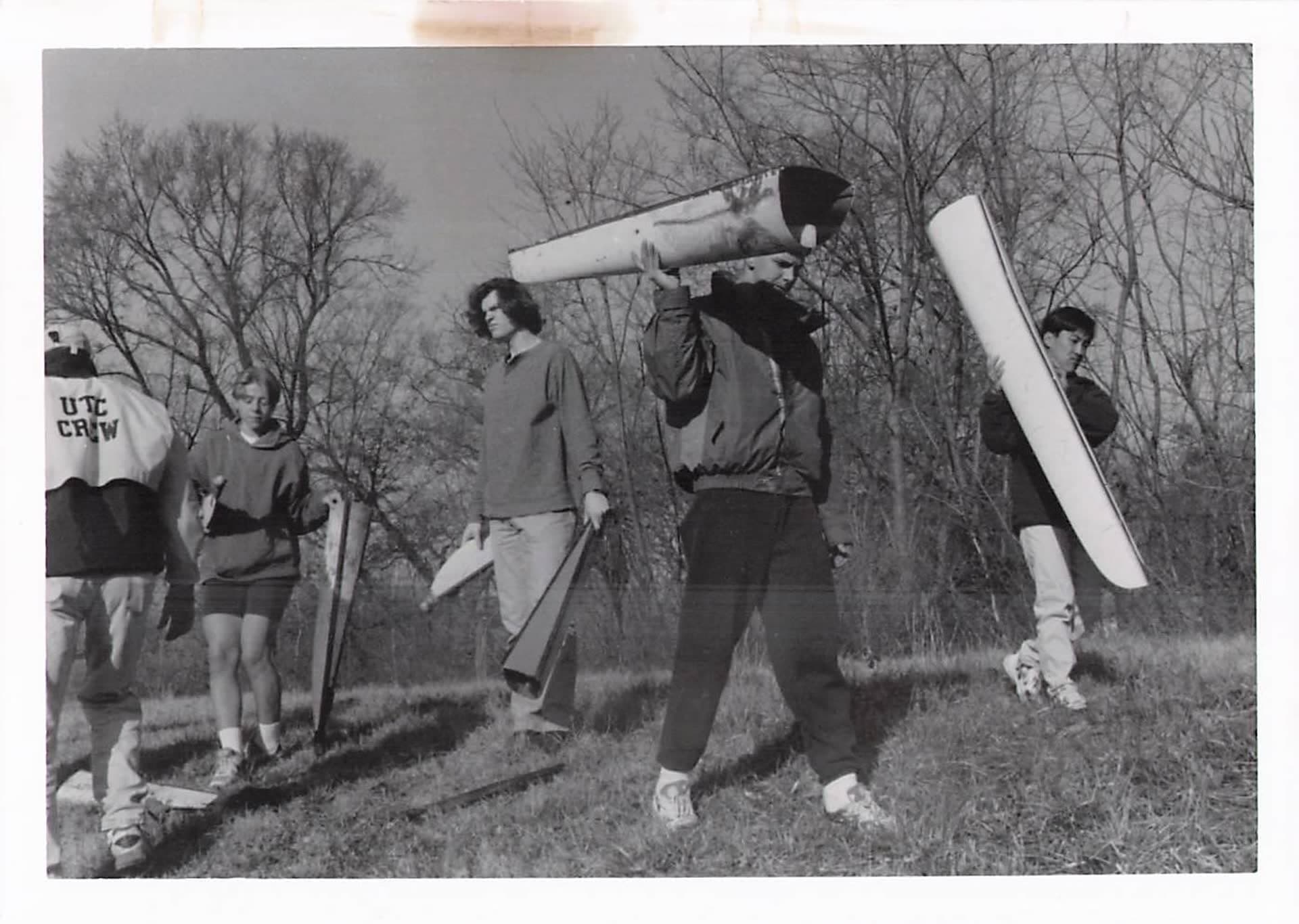UTC Rowing athletes carrying damaged shells through a field in 1996, after a trailer arson destroyed much of the program's fleet