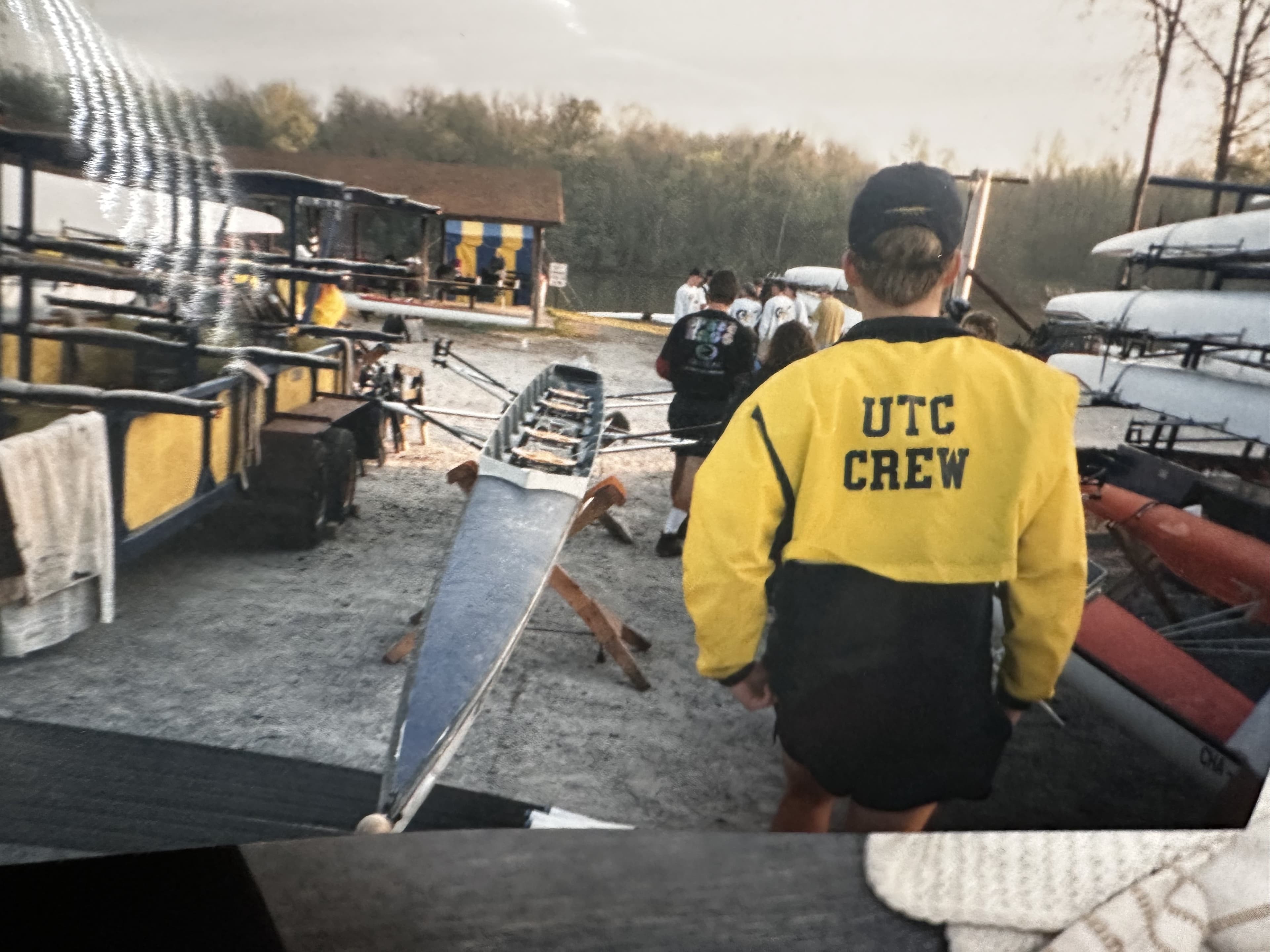 Boathouse scene, person walking away in yellow/black UTC CREW jacket