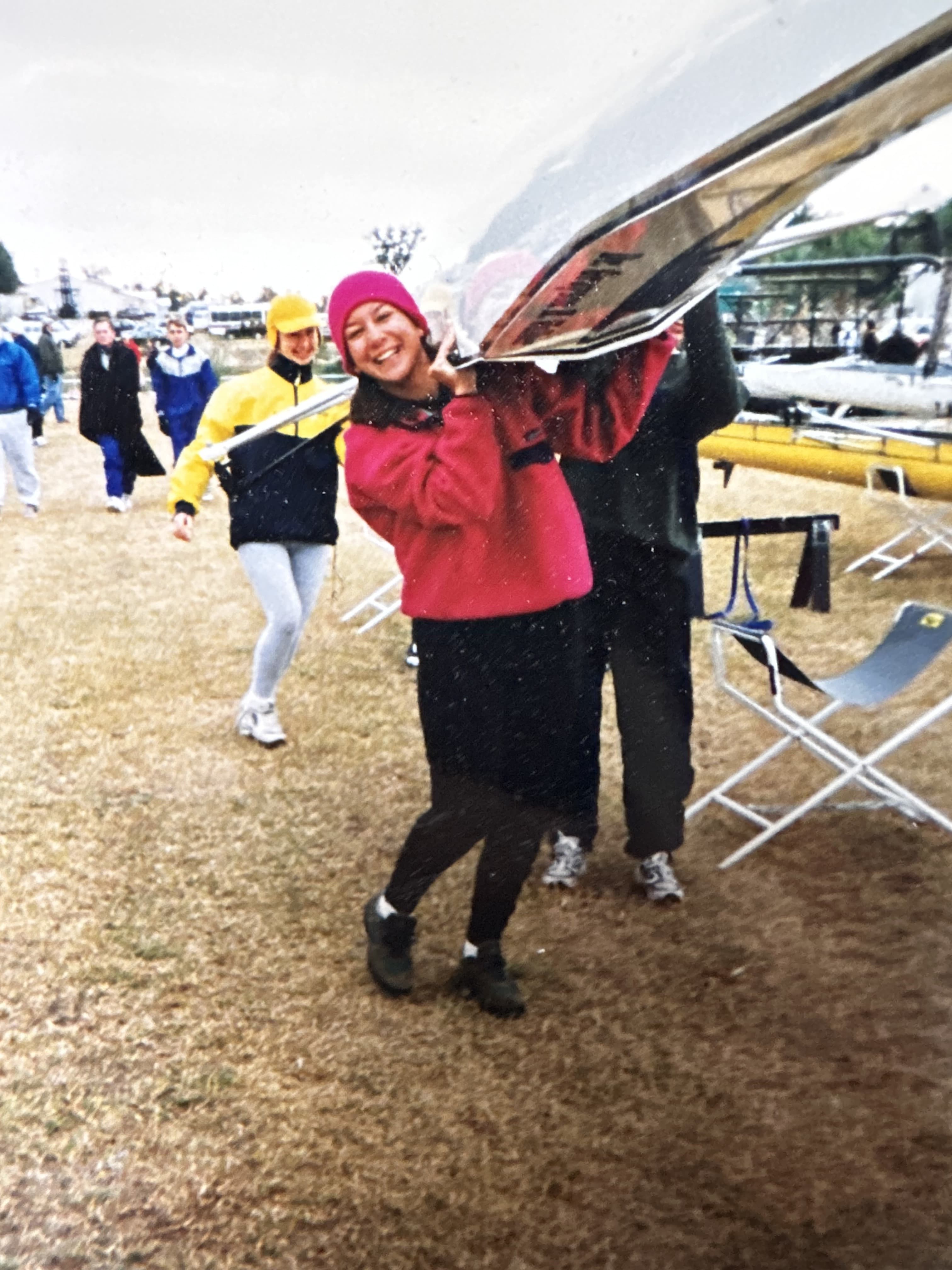 Solo rower at a regatta site (pink hat, red jacket, white pants)