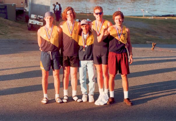 Men's medal group at a waterfront regatta — five UTC rowers in yellow/black kit