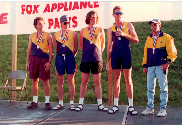 Men's medal podium under a Fox Appliance Parts banner — five UTC rowers in yellow/black kit