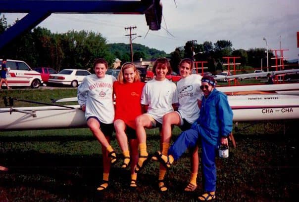 Four UTC women rowers and a coxswain sitting on top of the 'Cha-Cha' (Chattanooga) 4+ at golden hour, post-race